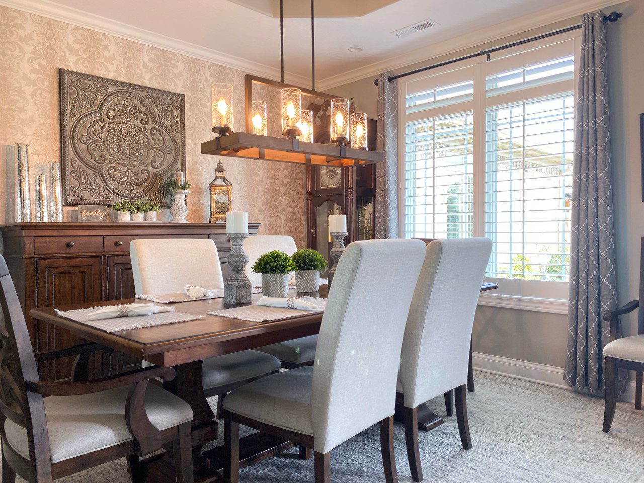 A dining room table with white chairs and a chandelier.