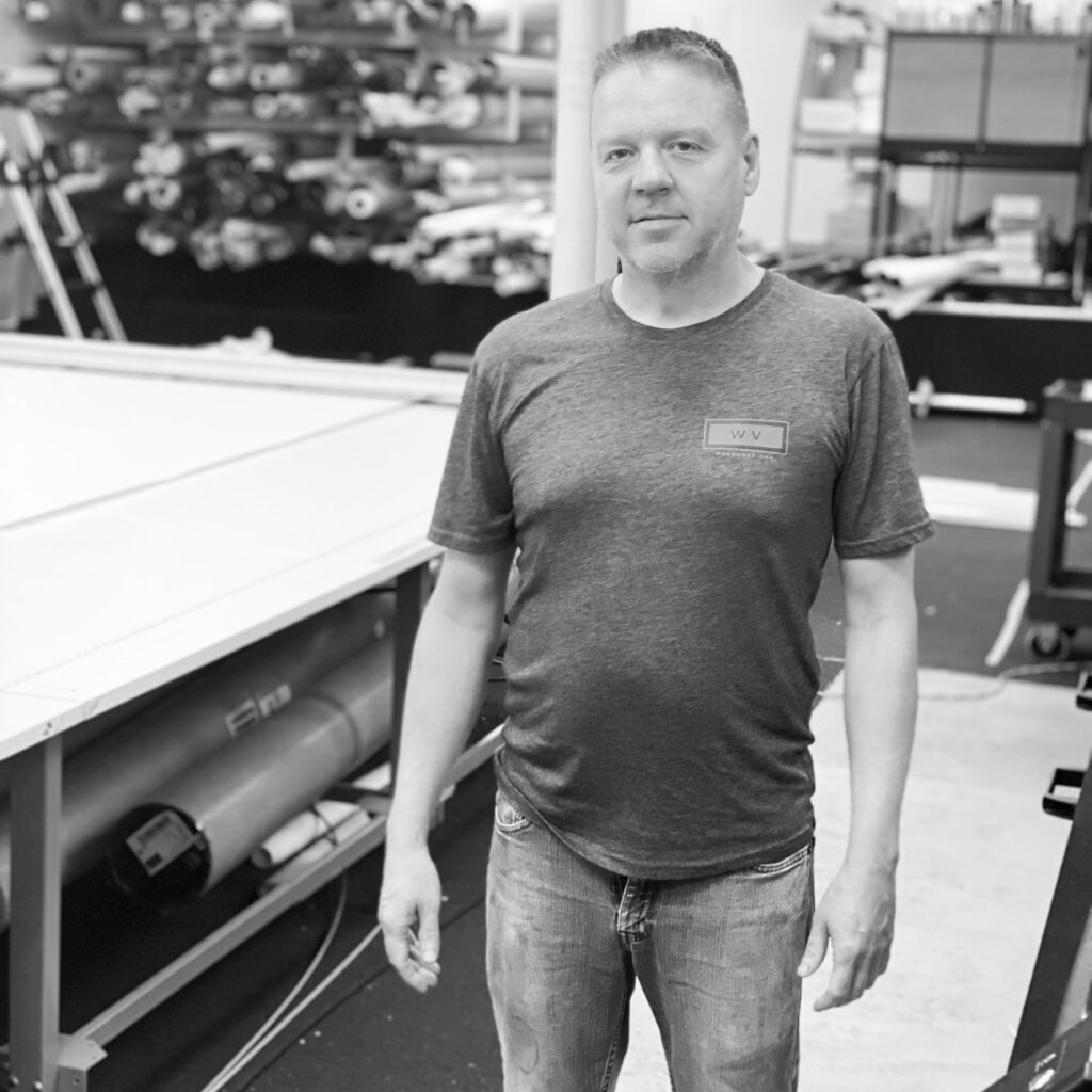 A man standing in front of a table tennis machine.