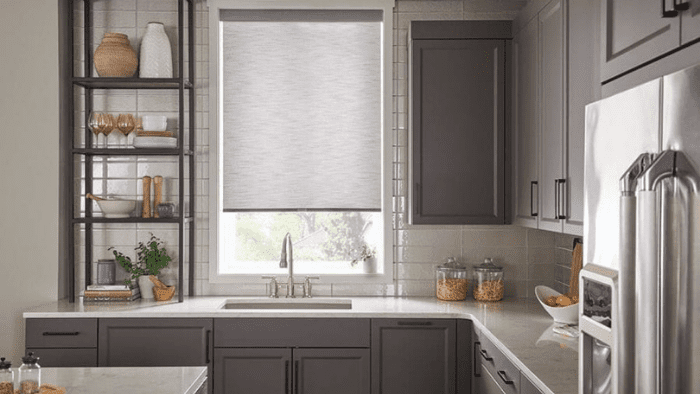 A kitchen with a sink and window covered in blinds.