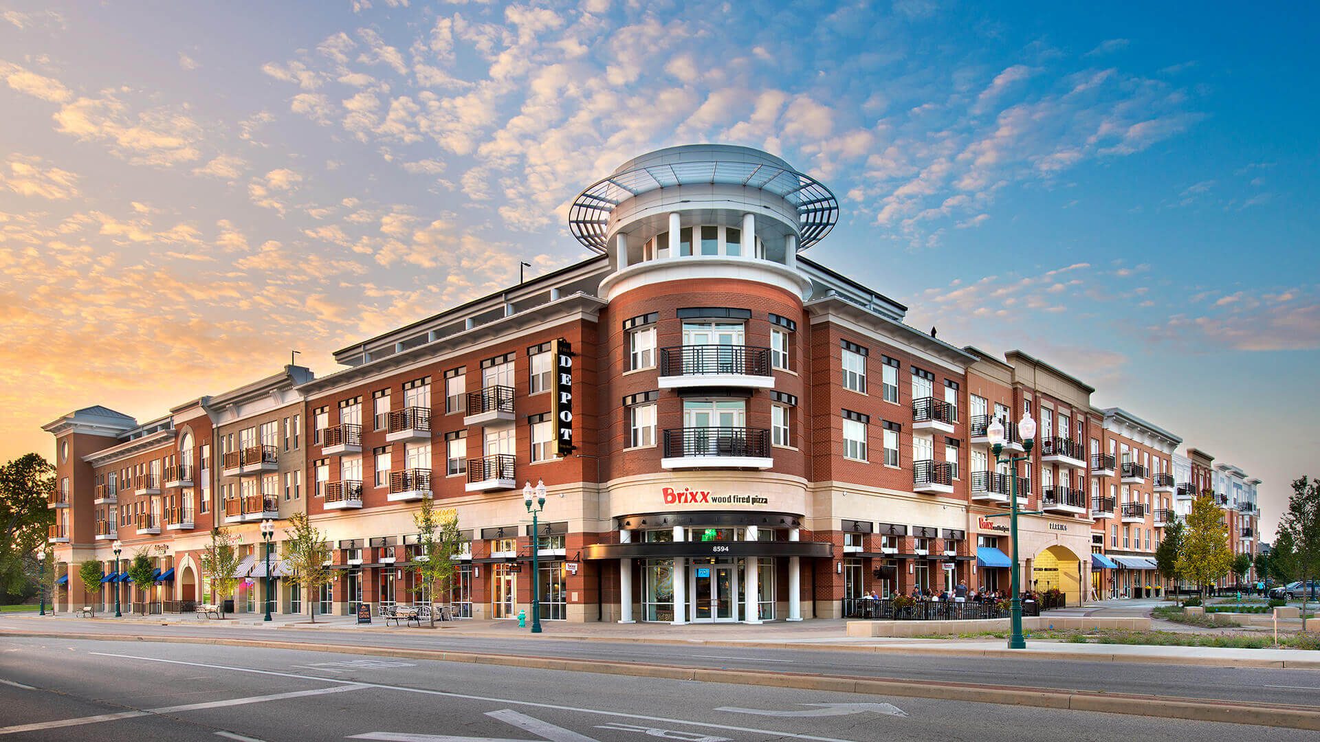 A large building with many windows on the corner of a street.