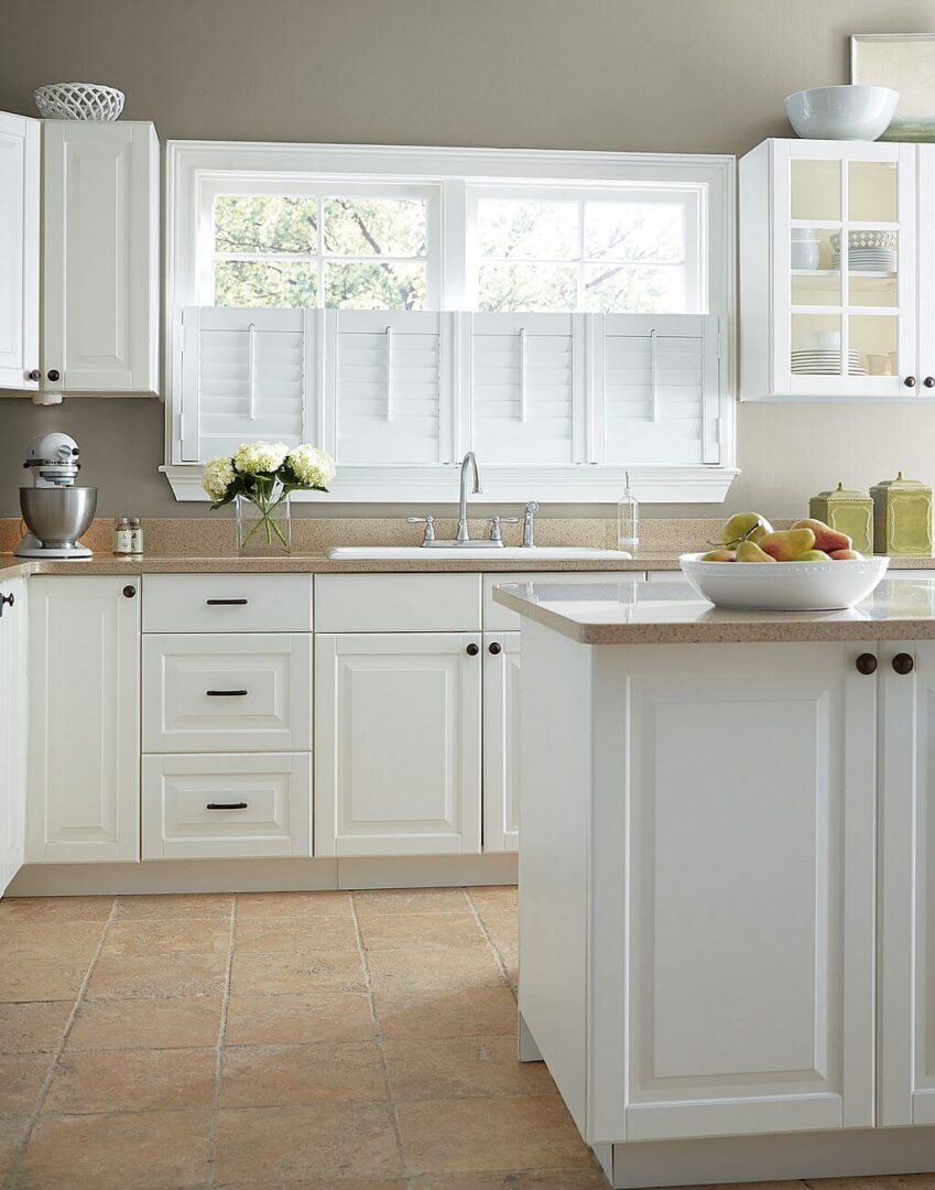 A kitchen with white cabinets and beige tile floors.