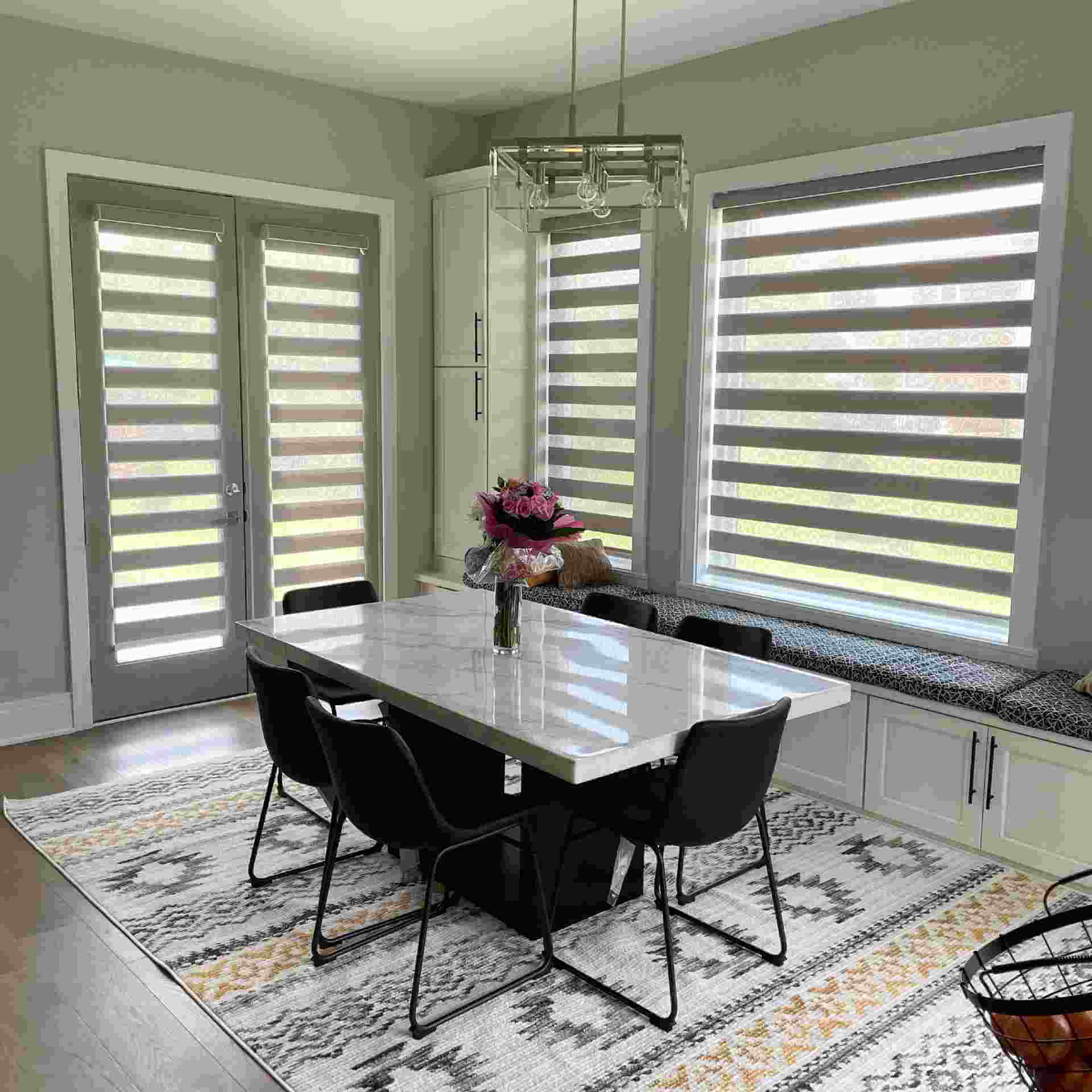 A dining room table with chairs and a vase of flowers.