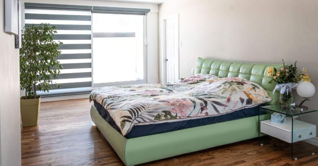 A bed with green headboard and floral comforter.