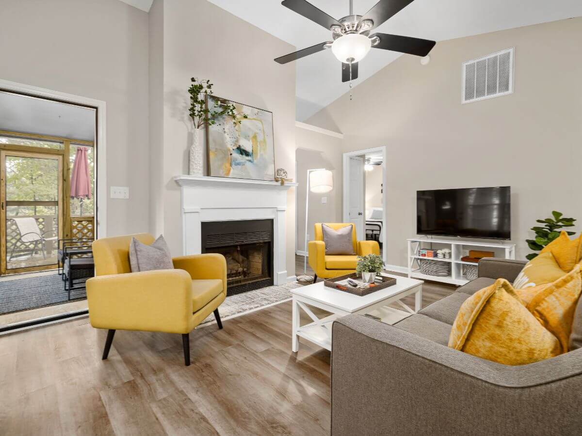 A living room with yellow chairs and a fireplace.